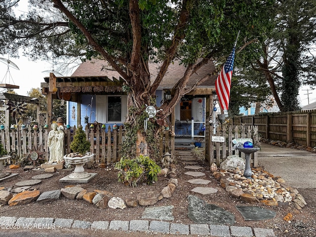 view of front of home with roof with shingles and fence