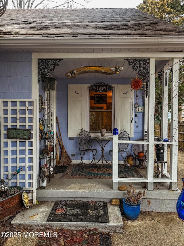 property entrance with covered porch and roof with shingles