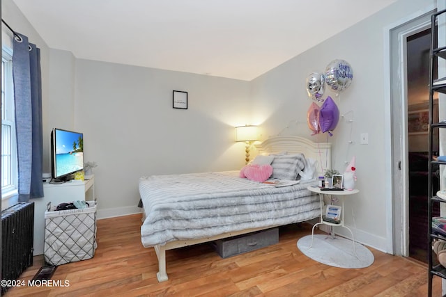 bedroom with radiator heating unit and hardwood / wood-style flooring