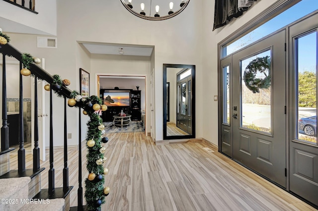 entrance foyer featuring light hardwood / wood-style floors, an inviting chandelier, and a high ceiling