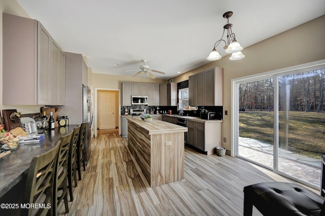 kitchen featuring wood counters, light wood-type flooring, backsplash, and gray cabinetry