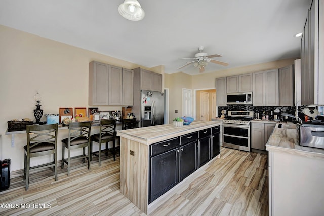 kitchen with ceiling fan, stainless steel appliances, gray cabinetry, and backsplash