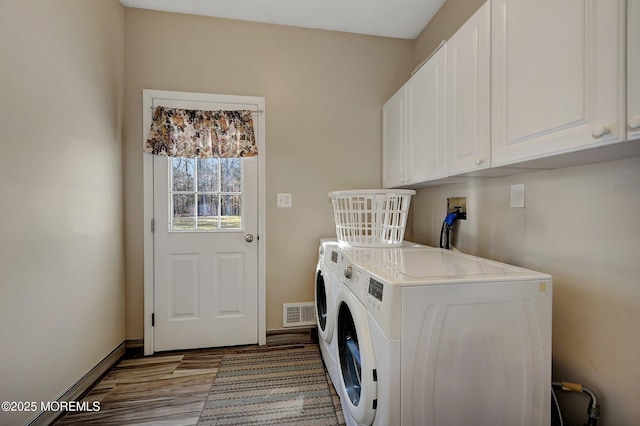 washroom with cabinets, hardwood / wood-style flooring, and separate washer and dryer