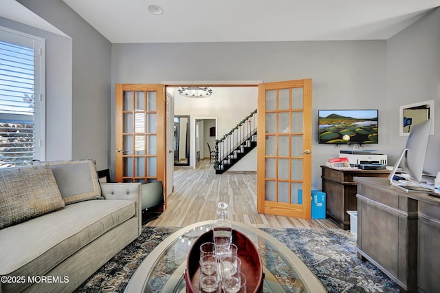 living room with light hardwood / wood-style floors, a chandelier, and french doors