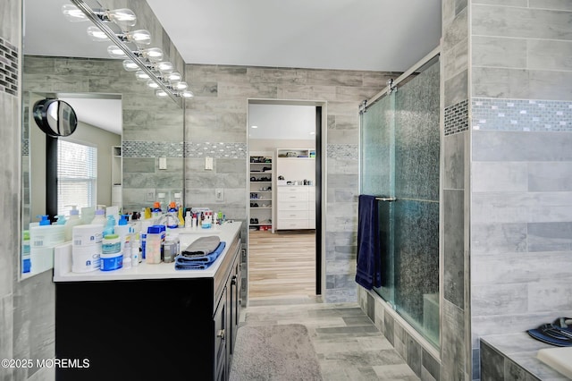 bathroom with separate shower and tub, tile walls, and vanity