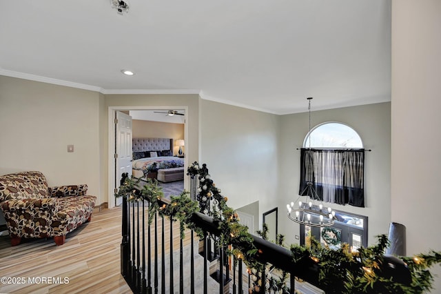 corridor featuring hardwood / wood-style floors, crown molding, and an inviting chandelier