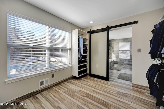 bedroom with a barn door and light hardwood / wood-style flooring