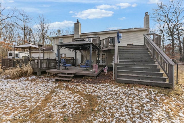 snow covered rear of property with a deck and a gazebo