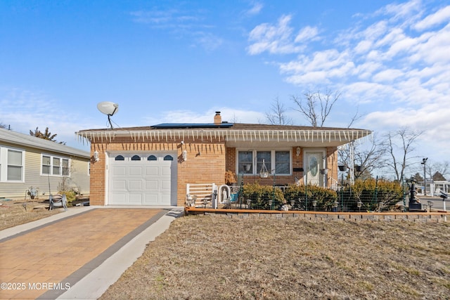 single story home with a garage and solar panels