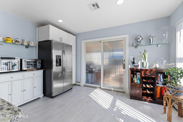 kitchen with white cabinetry, a baseboard radiator, stainless steel fridge with ice dispenser, and dark stone countertops