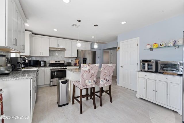 kitchen with a kitchen island, decorative light fixtures, white cabinetry, stainless steel appliances, and light stone countertops