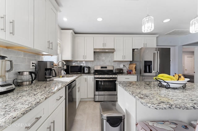 kitchen with white cabinetry, appliances with stainless steel finishes, decorative light fixtures, and backsplash