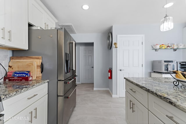 kitchen featuring tasteful backsplash, light stone countertops, white cabinets, stainless steel fridge with ice dispenser, and decorative light fixtures