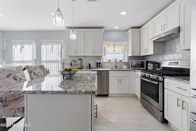 kitchen with a kitchen breakfast bar, a center island, white cabinets, and appliances with stainless steel finishes