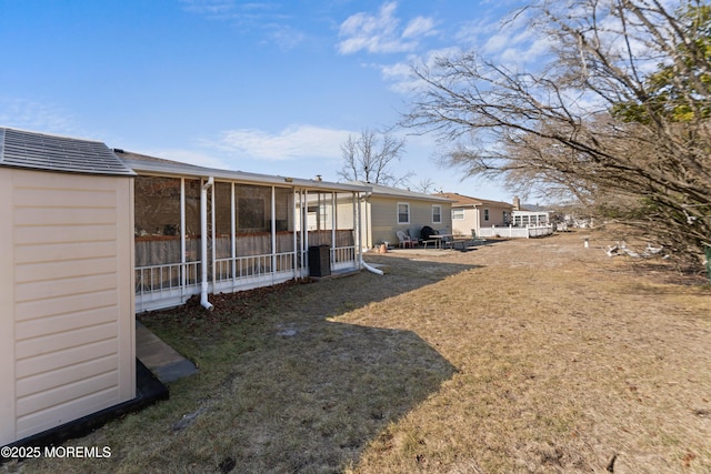 rear view of property featuring a lawn and a sunroom