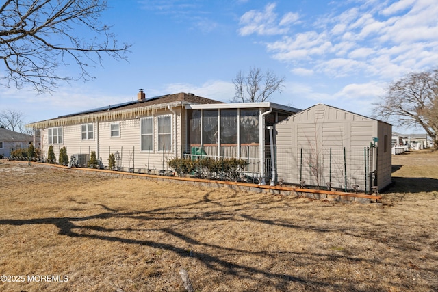 back of property with a sunroom and a lawn