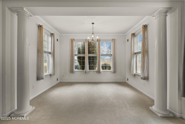 carpeted spare room with crown molding, decorative columns, and a wealth of natural light