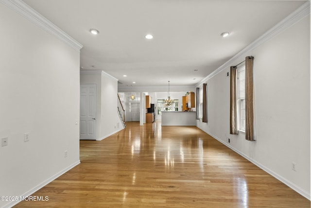 unfurnished living room featuring light wood-type flooring, a chandelier, plenty of natural light, and ornamental molding