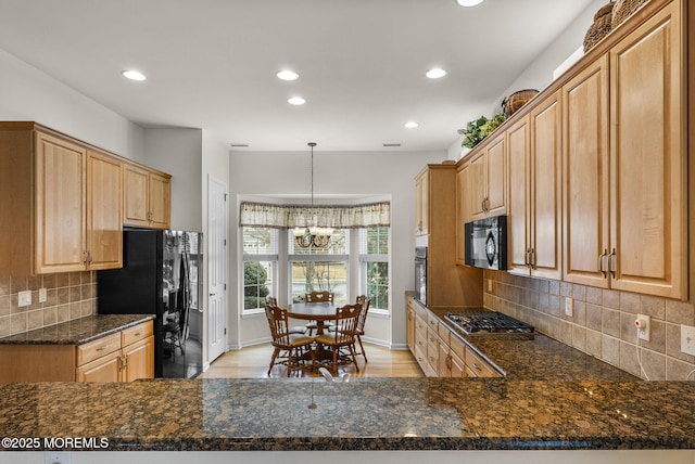 kitchen with dark stone countertops, black appliances, decorative light fixtures, decorative backsplash, and kitchen peninsula