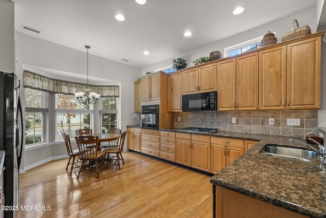 kitchen with sink, black appliances, tasteful backsplash, and pendant lighting