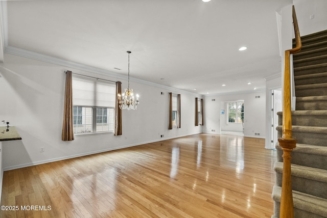 unfurnished living room with light hardwood / wood-style flooring, crown molding, and an inviting chandelier