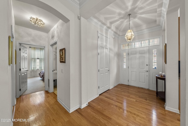 foyer entrance with a tray ceiling, hardwood / wood-style flooring, and crown molding