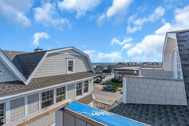 exterior space featuring roof with shingles, a chimney, and a gambrel roof