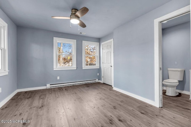 unfurnished bedroom featuring baseboard heating, ceiling fan, light hardwood / wood-style floors, and connected bathroom