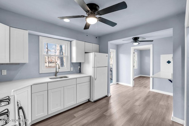 kitchen featuring white fridge, sink, gas range, and white cabinets