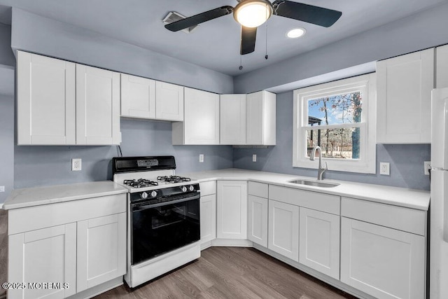 kitchen featuring sink, white cabinetry, ceiling fan, range with gas cooktop, and hardwood / wood-style flooring