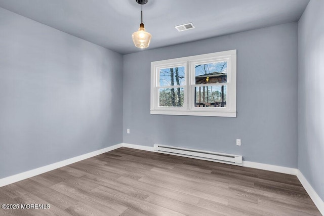 empty room featuring light wood-type flooring and a baseboard heating unit