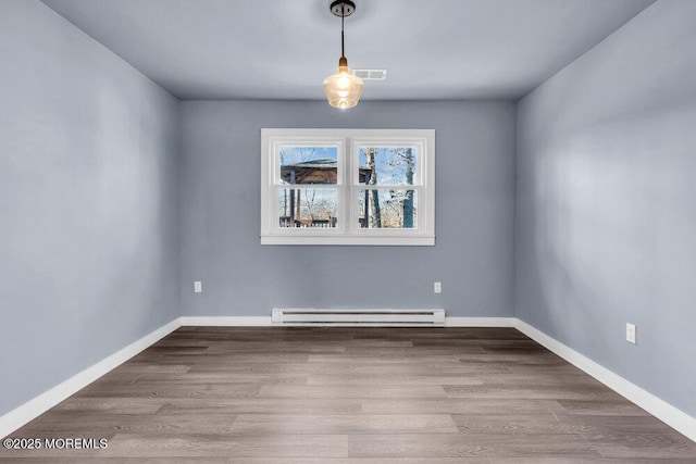 unfurnished dining area featuring wood-type flooring and a baseboard heating unit