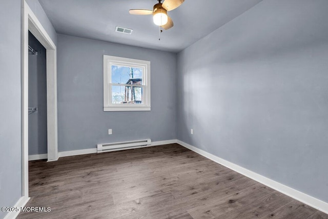 spare room with ceiling fan, wood-type flooring, and a baseboard heating unit