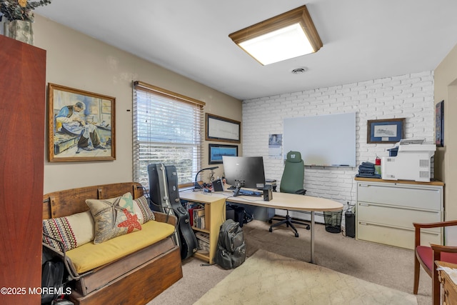 office space with light colored carpet, visible vents, and brick wall