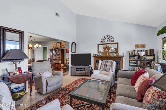 carpeted living area with a chandelier, high vaulted ceiling, and visible vents