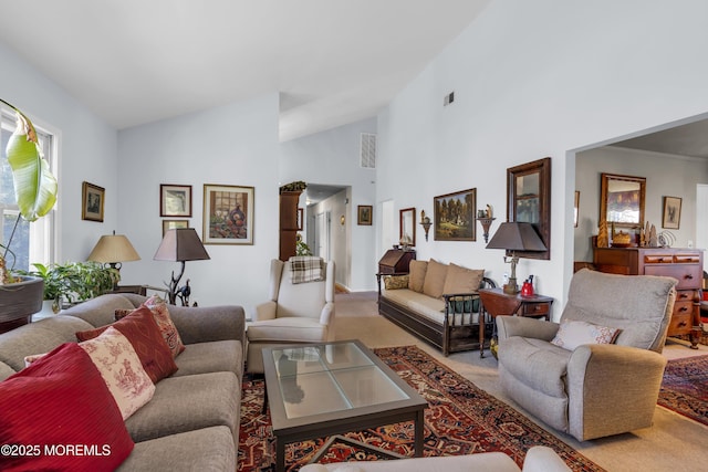 living area featuring high vaulted ceiling, light carpet, and visible vents