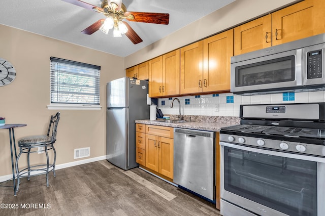 kitchen with sink, tasteful backsplash, dark hardwood / wood-style floors, ceiling fan, and stainless steel appliances