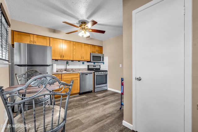 kitchen featuring dark hardwood / wood-style floors, tasteful backsplash, sink, stainless steel appliances, and a textured ceiling