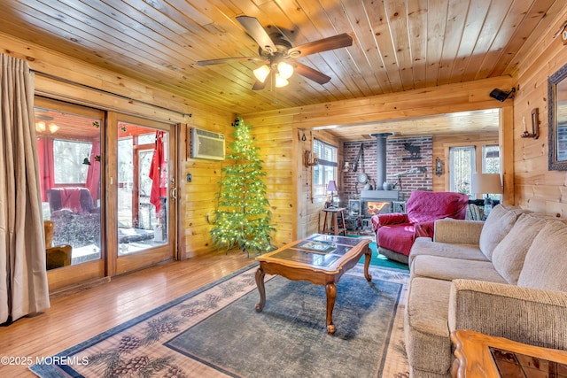 living room with a wood stove, a healthy amount of sunlight, wood-type flooring, and a wall mounted AC