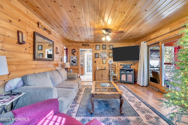 living room featuring a ceiling fan, wood ceiling, wood walls, and wood finished floors