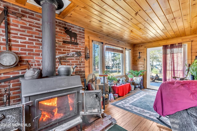 living area featuring hardwood / wood-style flooring, wooden ceiling, a wood stove, and wooden walls