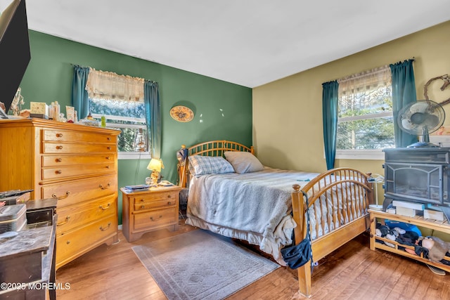 bedroom with a wood stove and hardwood / wood-style flooring