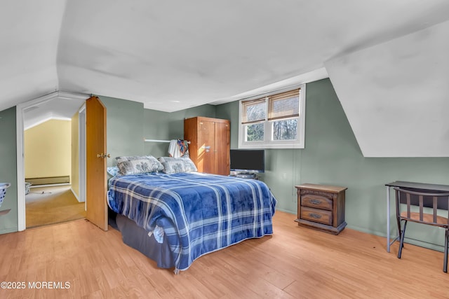 bedroom with vaulted ceiling, a baseboard radiator, and wood finished floors