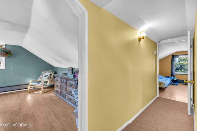 corridor featuring lofted ceiling, baseboards, and wood finished floors