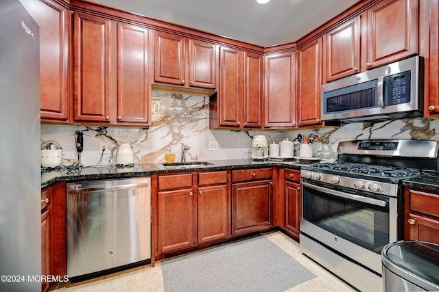 kitchen with stainless steel appliances, tasteful backsplash, sink, and dark stone countertops