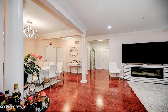 living room with decorative columns, wood-type flooring, ornamental molding, and a chandelier