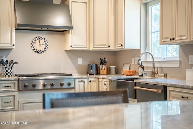 kitchen with appliances with stainless steel finishes, a sink, and wall chimney range hood