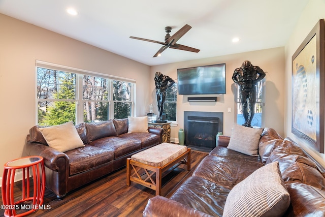 living area with recessed lighting, a ceiling fan, wood finished floors, and a glass covered fireplace