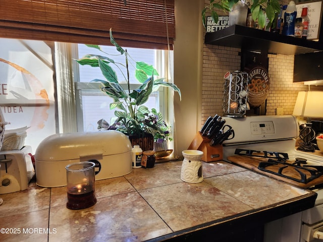 kitchen with tasteful backsplash, tile patterned flooring, white range with gas cooktop, and wall chimney range hood