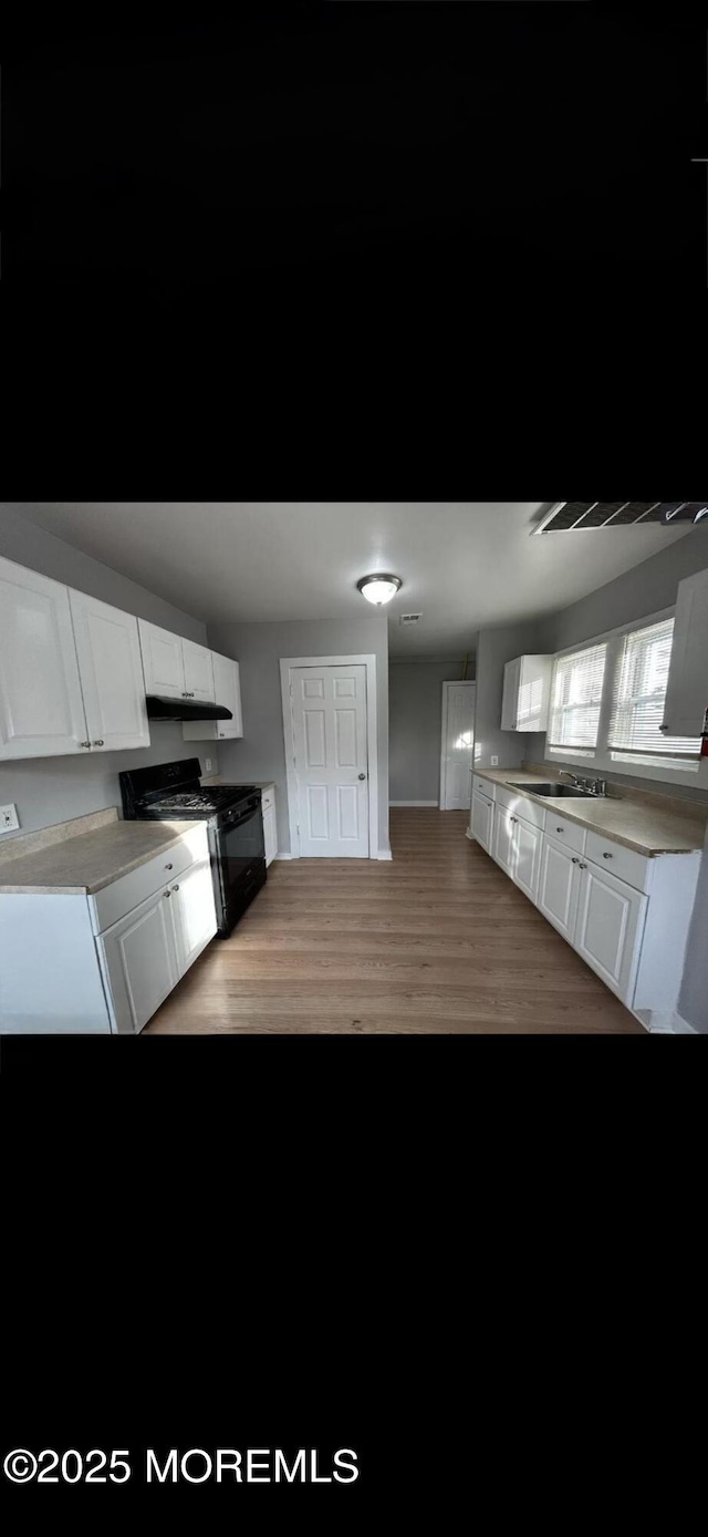 kitchen with white cabinetry, sink, light wood-type flooring, and gas stove